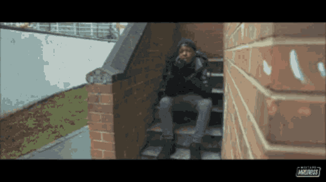 a man is sitting on a set of stairs in front of a brick wall with the word ambush on it