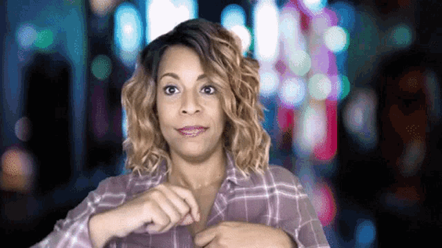 a woman wearing a plaid shirt is looking at the camera