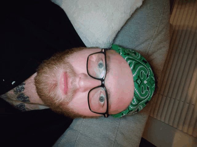 a man wearing glasses and a green bandana with the letter s on it