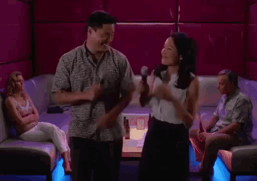 a man and woman are giving each other a high five in a karaoke room .