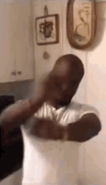 a man in a white shirt is standing in a kitchen holding a pillow .