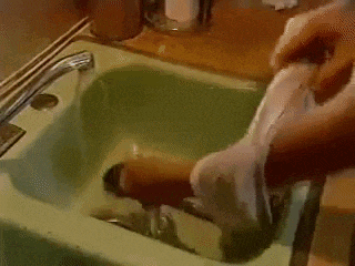 a person is washing a white shirt in a green sink