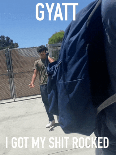 a man with a backpack is standing in front of a fence with a caption that says gyatt i got my shit rocked
