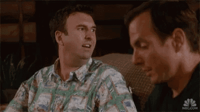 two men are sitting next to each other on a couch and talking .