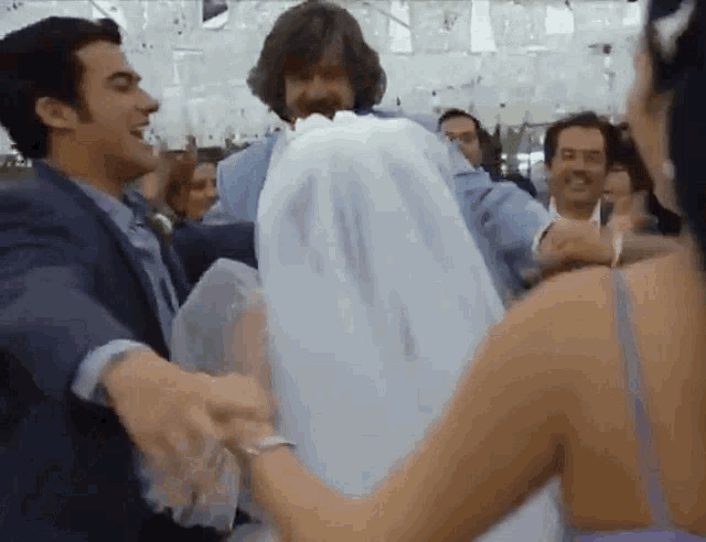 a man in a suit is carrying a woman in a wedding dress on his shoulders .