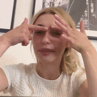 a woman covering her eyes with her hands in front of a picture