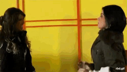 two women standing next to each other with a yellow wall behind them and the url rbd.gif visible