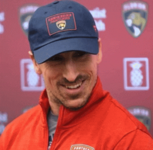 a man wearing a panthers hat is smiling