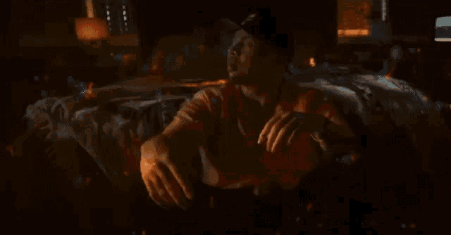a man in a baseball cap is sitting on a bed in a dark room surrounded by bubbles .