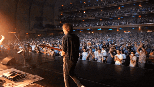 a man playing a guitar in front of a crowd of people