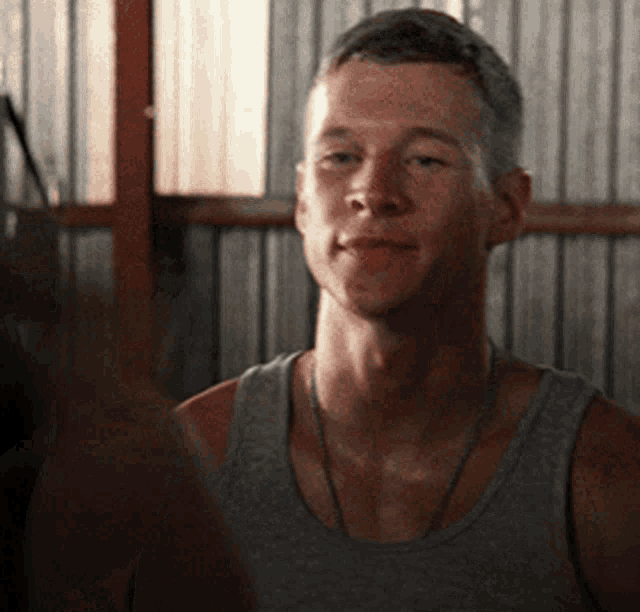 a man wearing a grey tank top looks at another man