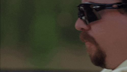 a close up of a man wearing sunglasses and a scarf around his neck