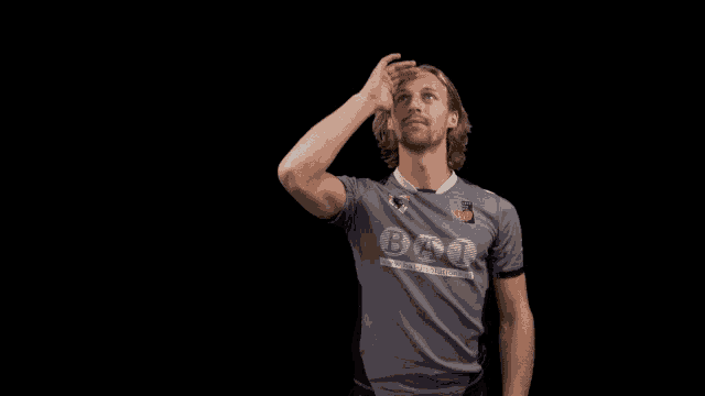 a man wearing a bat shirt throws a ball in the air