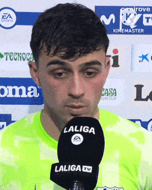 a man speaking into a laliga tv microphone while wearing a green jersey