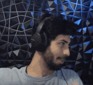 a man with a beard is wearing headphones and smiling in front of a blue wall .