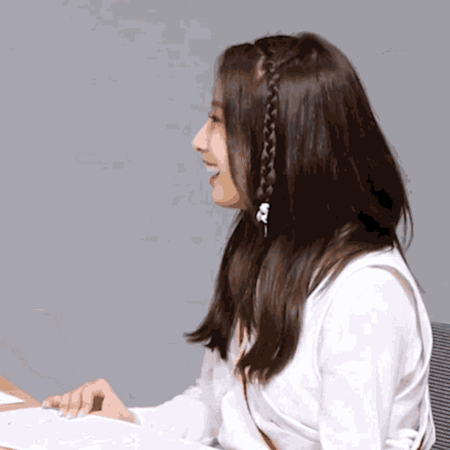a woman with a braid in her hair is sitting at a table
