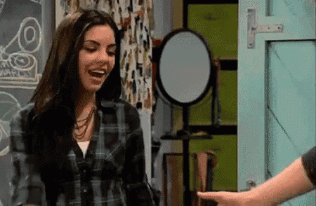 a woman in a plaid shirt is laughing while standing next to a man in front of a mirror .