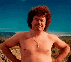 a shirtless man with curly hair is standing with his hands on his hips and a cross necklace .