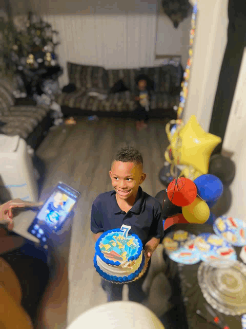 a young boy is holding a blue cake with the number 7 on it