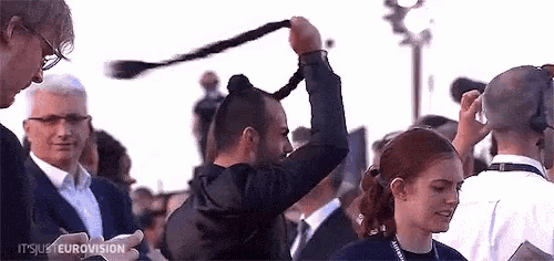 a man is holding a woman 's hair in a bun in a crowd .
