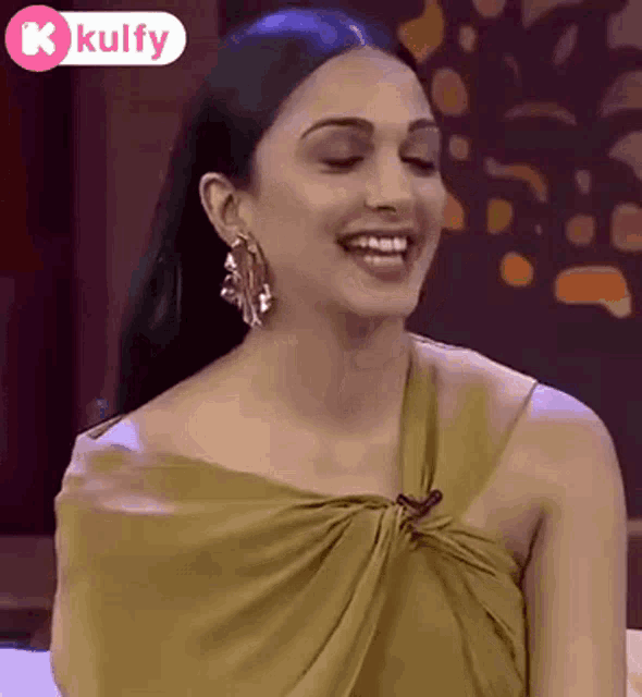 a woman in a yellow dress is smiling and wearing earrings
