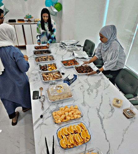 a group of people are gathered around a table with plates of food and a box of tissues