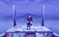 a man is standing on a platform overlooking a body of water with mountains in the background .