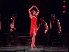 a woman in a red dress dancing on a stage