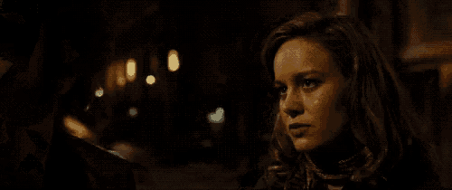 a woman is smiling in a dark room and looking at the camera .