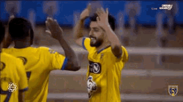 a group of soccer players are giving each other a high five on a soccer field .