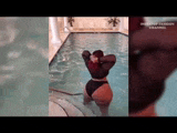 a woman in a bikini is standing in a pool .
