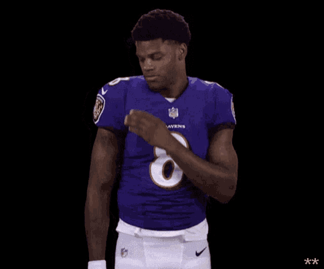 a ravens football player wearing a purple jersey and white pants