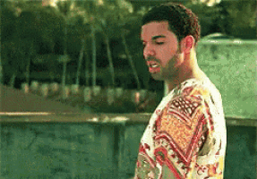 a man with a beard and a floral shirt is standing in front of a wall .