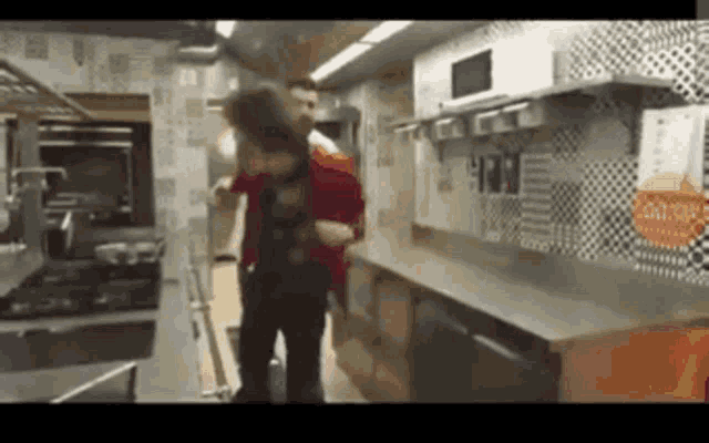 a man in a red jacket is standing in a kitchen next to a counter