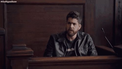 a man in a leather jacket giving a thumbs up in a courtroom