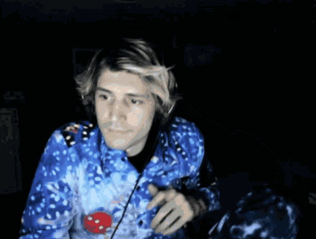 a man wearing a blue tie dye shirt giving a thumbs up