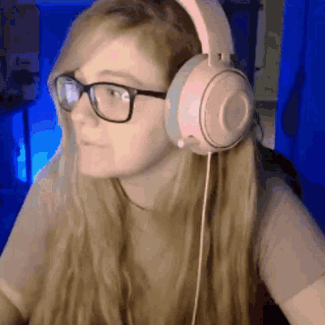 a woman wearing glasses and pink headphones is sitting at a computer .