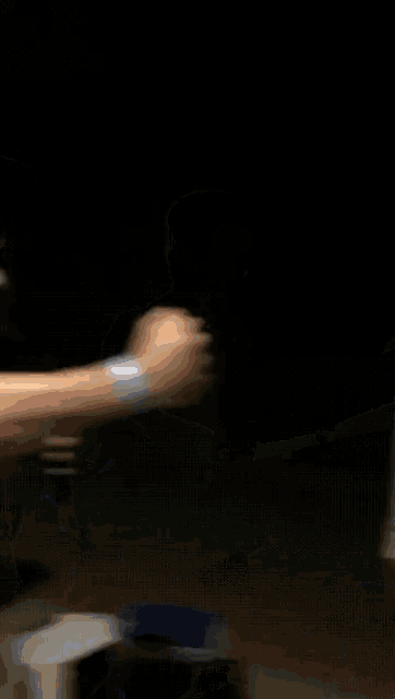 a man in a blue shirt is standing in a dark room with his arms outstretched