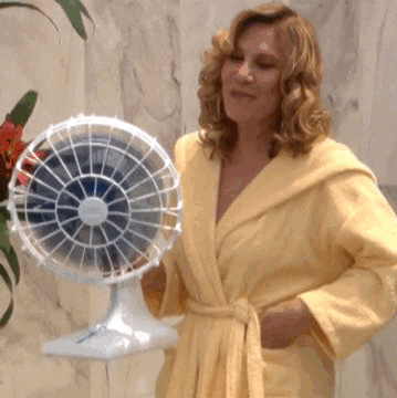 a woman in a yellow robe is holding a white fan
