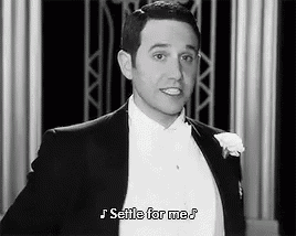 a man in a tuxedo and bow tie is singing a song .