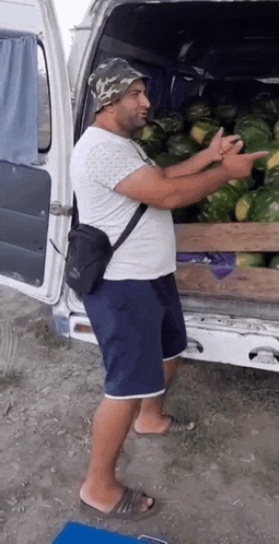 a man in a hat is standing in front of a van full of watermelons