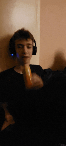 a young man wearing headphones holds a hot dog in his hand