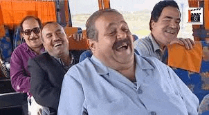 a group of men are laughing and sitting on a bus .