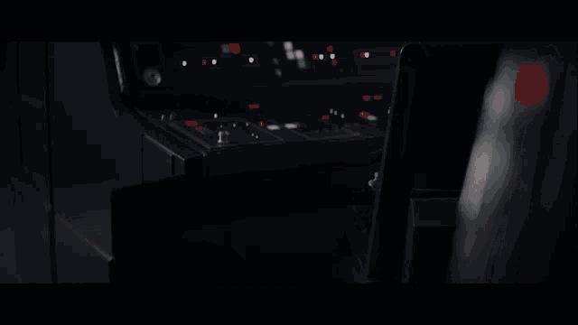 a baby yoda is sitting in a dark room looking out of a window