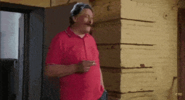 a man with a mustache is smoking a cigarette and pointing at the camera .