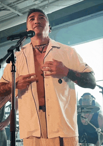 a shirtless man stands in front of a microphone with his shirt off