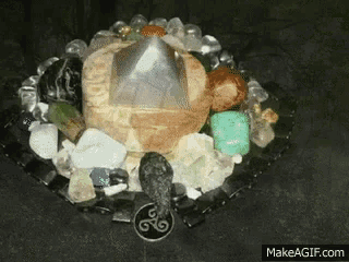 a display of crystals and stones with a triskelion pendant