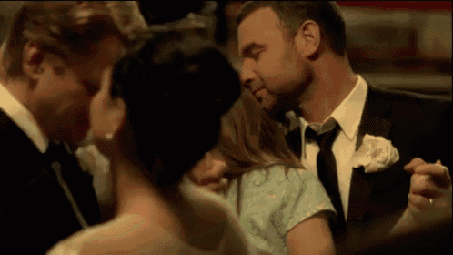 a man in a suit and tie is kissing a woman on the cheek