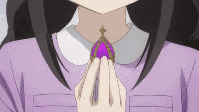 a girl in a purple shirt is holding a purple pendant