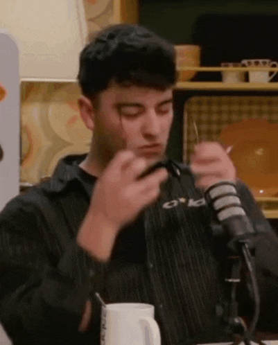 a man is sitting at a table with a microphone and a cup of coffee .